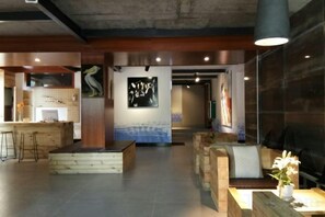 Een moderne lobby met een receptiebalie, een zithoek en kunstwerken aan de muren.