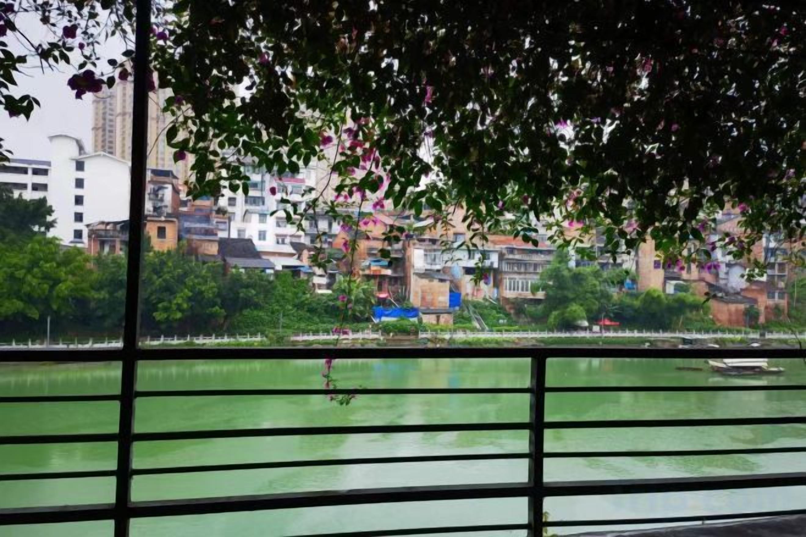 A view of a river with a bridge in the foreground and buildings in the background.