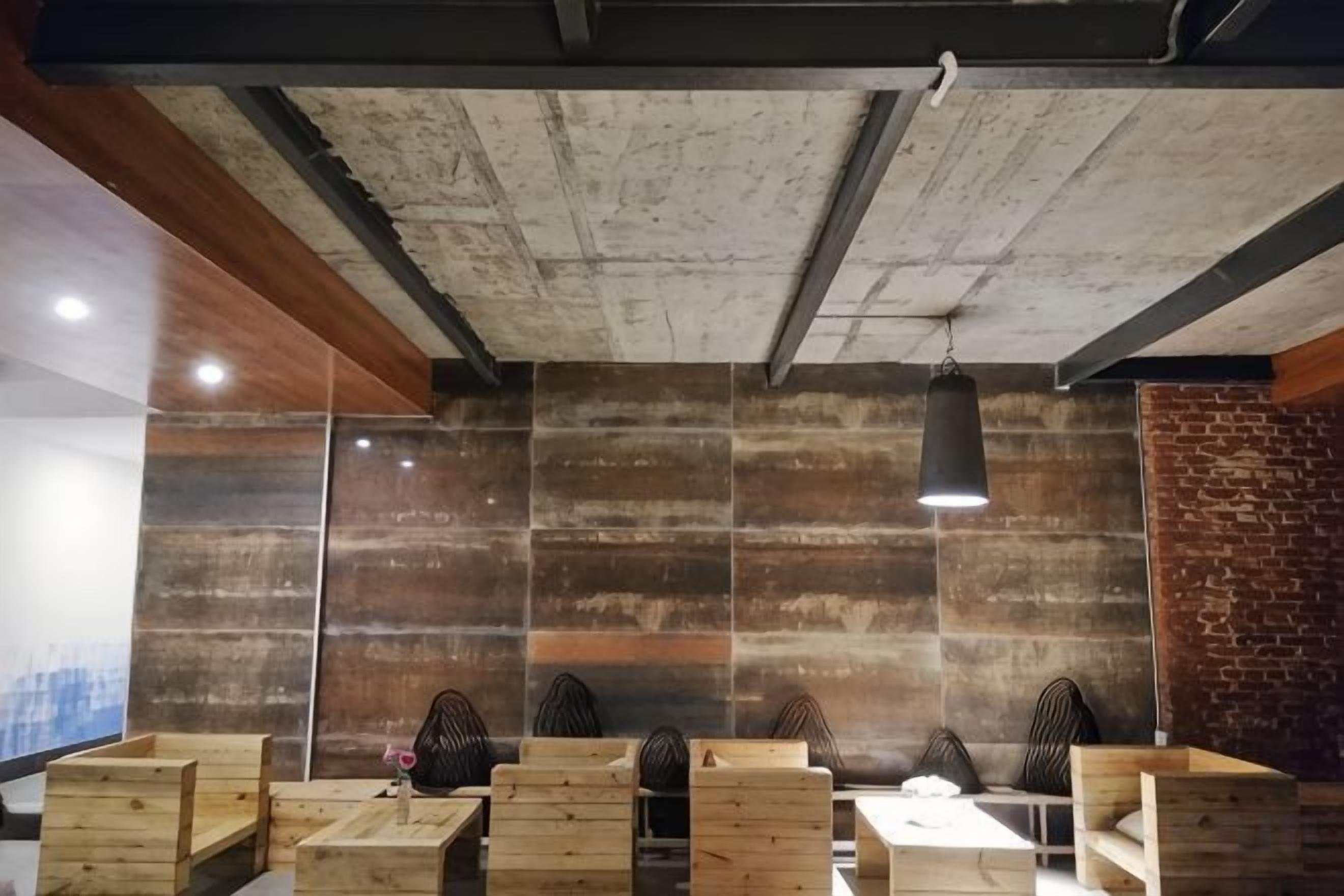 A modern interior with exposed concrete ceiling, wooden seating, and a brick accent wall.