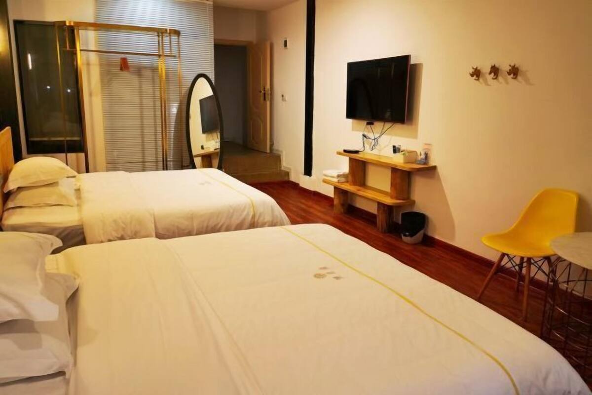 A hotel room with two beds, a TV, a mirror, a small table, and a chair.