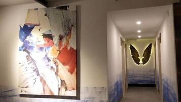 A hallway with a large abstract painting on the left and a wall-mounted illuminated design on the right.