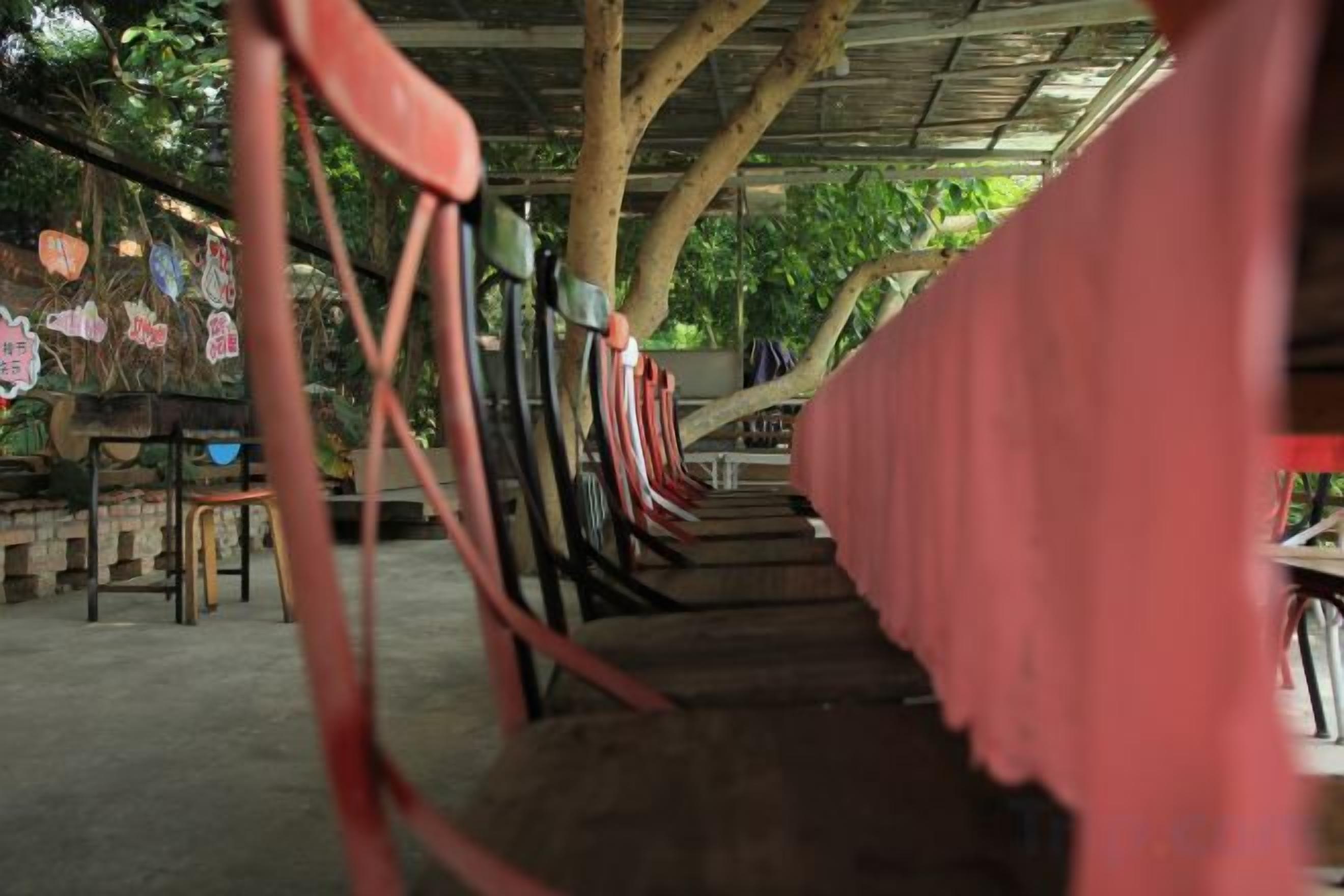 Une rangée de chaises en bois placée sous un espace abrité, avec une nappe rose.