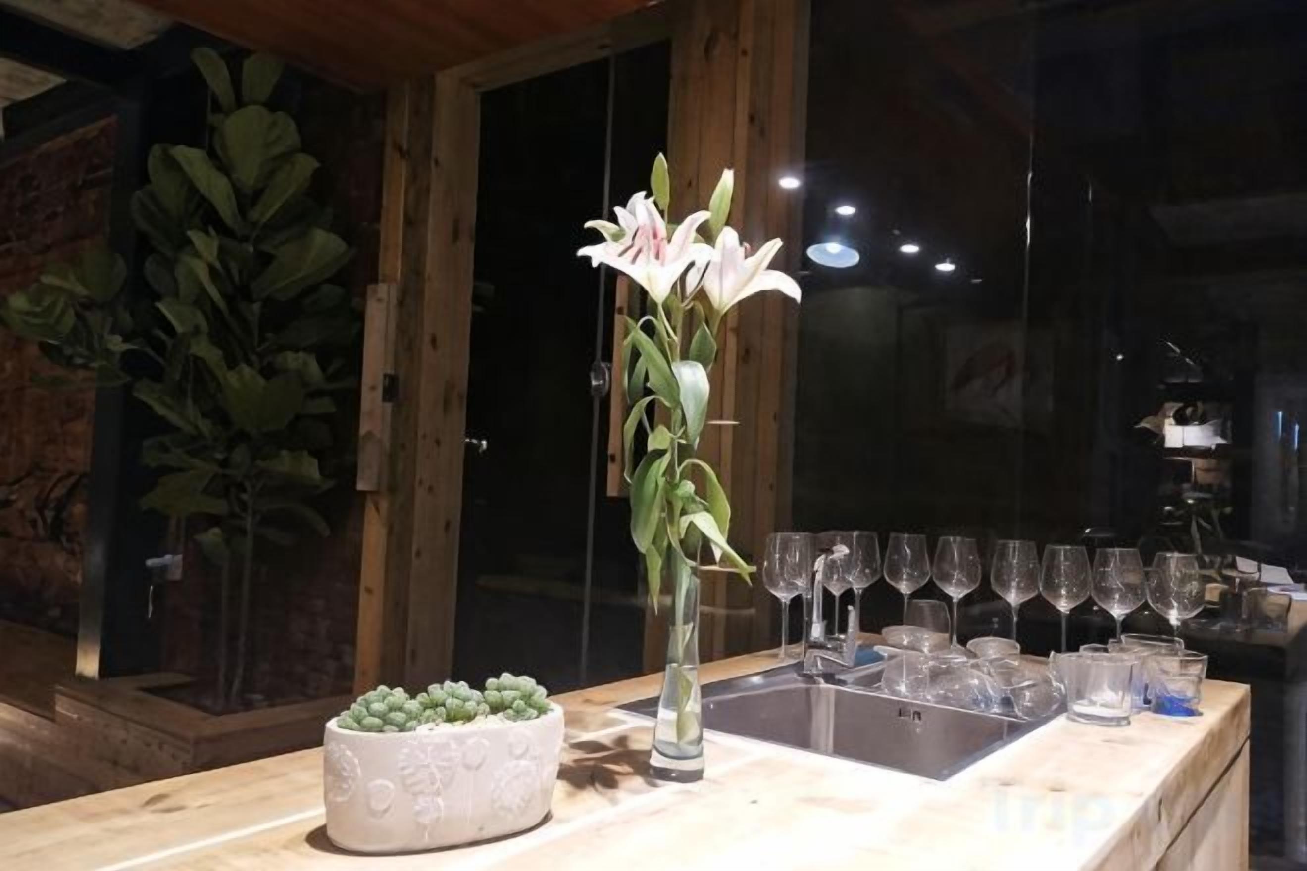 Un área de bar con un jarrón de flores, un cuenco de suculentas y una fila de vasos.