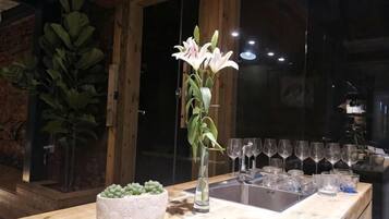 A bar area with a vase of flowers, a bowl of succulents, and a row of glasses.