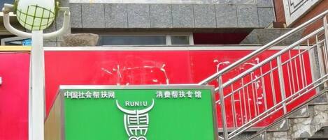 Un letrero de hotel con el nombre 'Amdo Express Hotel' y un letrero verde con caracteres chinos y un número de teléfono.