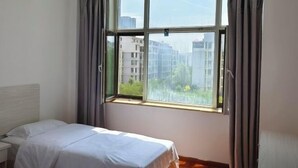 A bedroom with a bed, a window, and curtains.