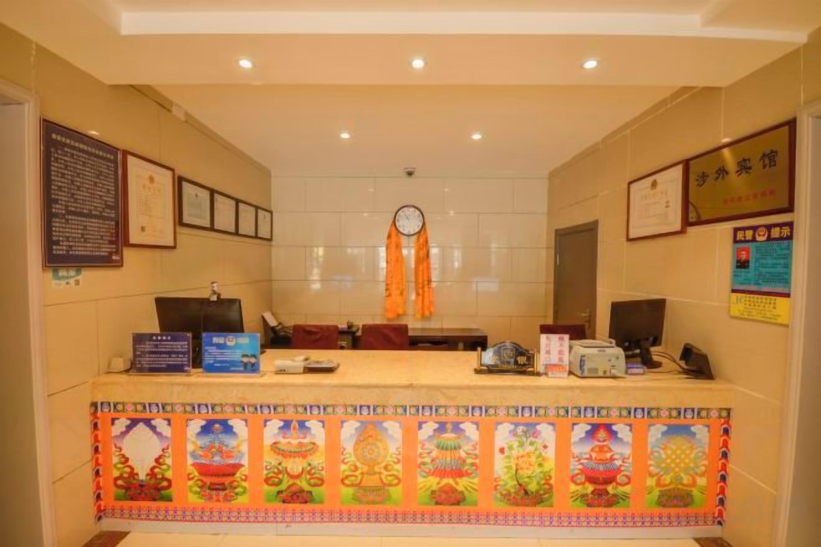 A reception desk with a clock, framed certificates, and a decorative border.