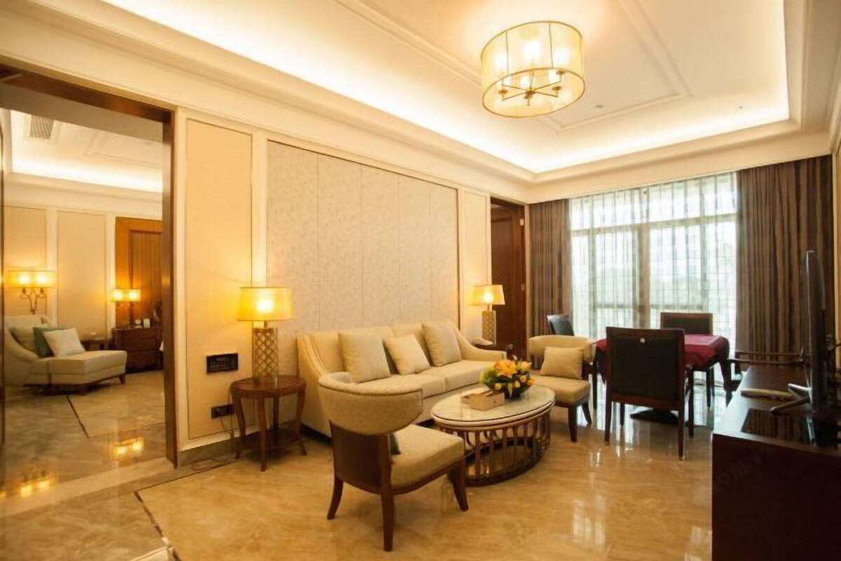 A well-lit living room with a sofa, armchairs, a coffee table, and a television.
