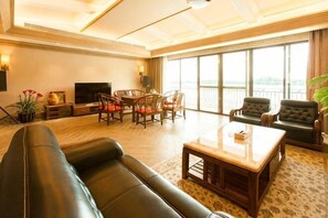 A spacious living room with a leather sofa, a wooden coffee table, and a dining area with chairs. - Hubin Hotel (Foshan)