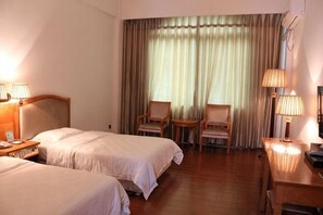 A hotel room with two beds, a desk, two chairs, a window with curtains, and lamps. - Hubin Hotel (Foshan)