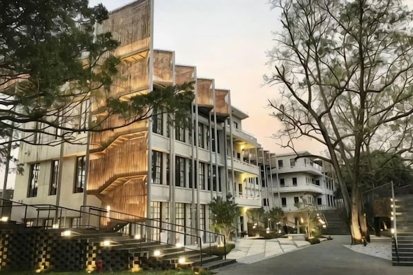 A multi-story hotel with a modern design, featuring balconies and a central staircase.