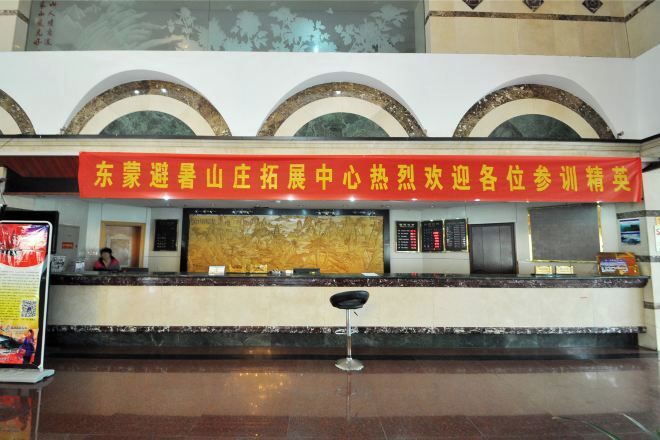 A hotel reception area with a red banner, a marble counter, and a reception desk.