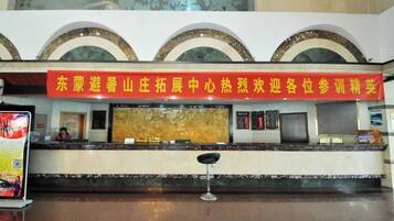 A hotel reception area with a red banner, a marble counter, and a reception desk.