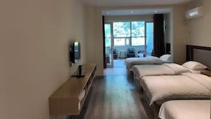 Ein Hotelzimmer mit zwei Betten, einem Fernseher, einem Schreibtisch und einem Fenster.
