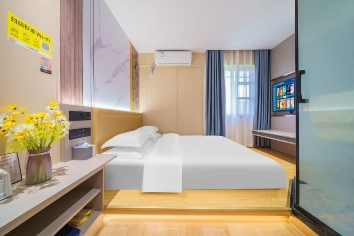 A hotel room with a bed, bedside table, and a TV.