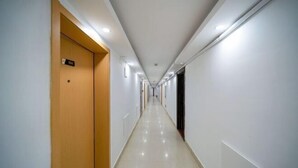 A long, narrow hotel corridor with a wooden door on the left and a black door on the right. - Apollo Hotel (Zhangzhou Ancient City) (Zhangzhou)