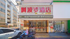 A hotel with a prominent red sign, a glass entrance, and a parking area with scooters. - Apollo Hotel (Zhangzhou Ancient City) (Zhangzhou)