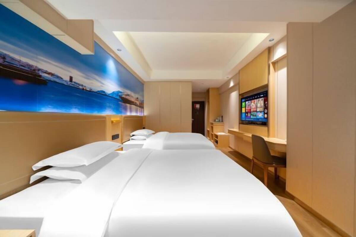 A hotel room with two beds, a large wall mural, a TV, and a desk with a chair.
