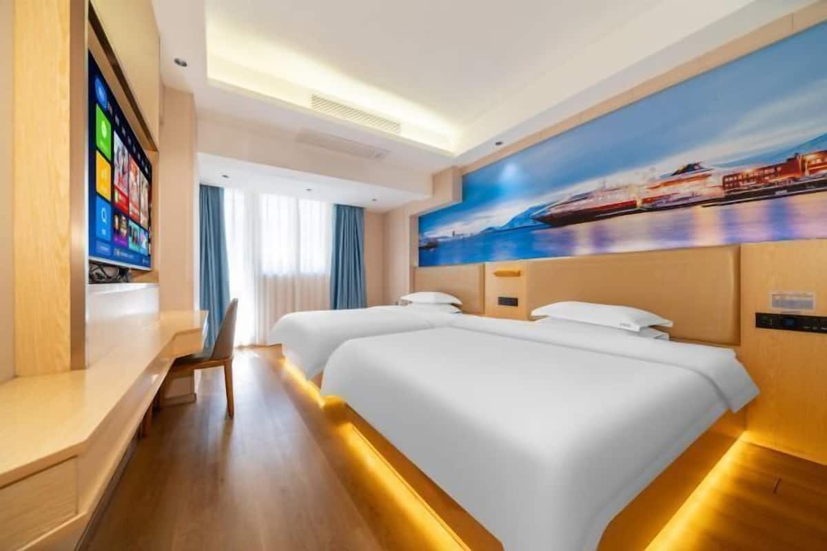 A hotel room with two beds, a TV on the left, and a painting of a waterfront scene on the wall.