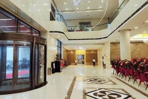 A hotel lobby with a glass entrance, a red carpet, and a seating area with chairs. - Ju Xiu Hotel (Zhen'an)