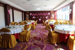 A banquet hall with round tables, yellow chairs, and a patterned carpet. - Ju Xiu Hotel (Zhen'an)