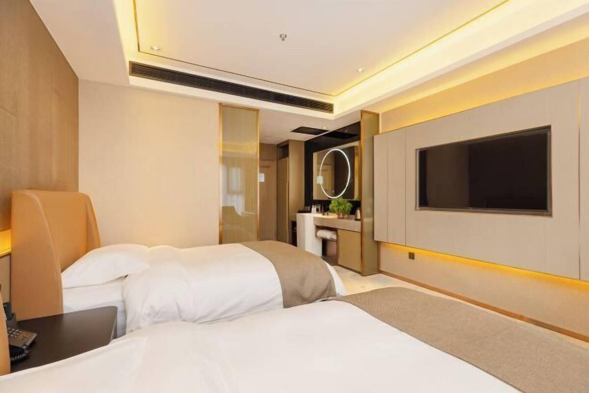 Una moderna camera d'hotel con un letto grande, una scrivania, una sedia, una TV e uno specchio.
