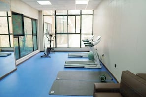 A room with exercise equipment, a treadmill, and a large window. - Ju Xiu Hotel (Zhen'an)