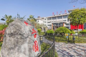 A stone monument with red inscriptions, a modern building with multiple floors, and a well-maintained garden area. - Ju Xiu Hotel (Zhen'an)