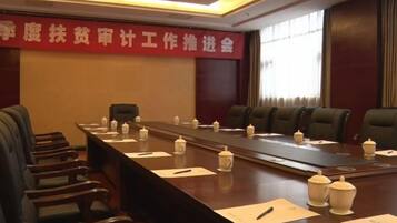 A conference room with a long table, chairs, and a banner on the wall.