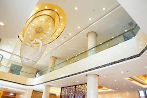A multi-level interior with glass railings, a hanging light fixture, and a patterned wall. - Ju Xiu Hotel (Zhen'an)