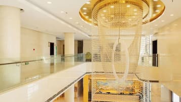 A spacious lobby with a large chandelier, a glass railing, and a central decorative structure.