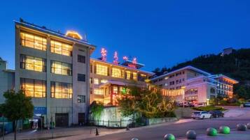 A hotel with multiple floors, a well-lit entrance, and a parking area with bollards.