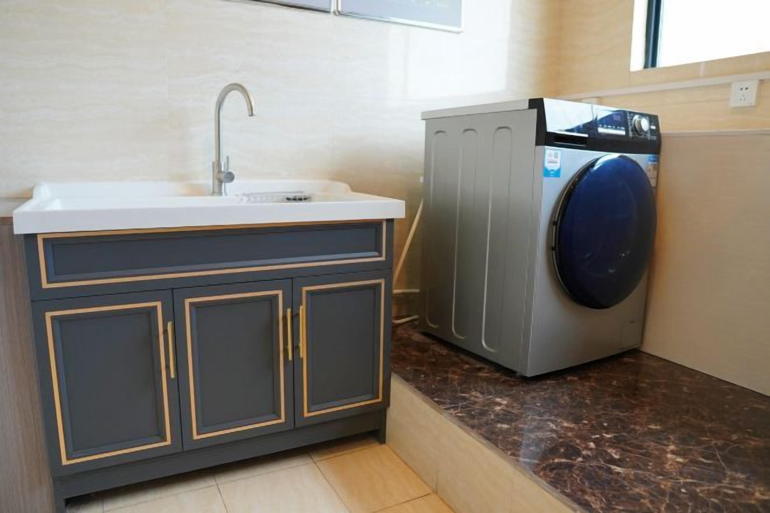 A compact kitchen with a sink, cabinets, and a washing machine.