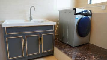 A compact kitchen with a sink, cabinets, and a washing machine.
