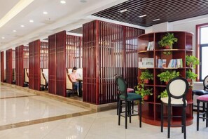 A modern interior with a reception desk, seating area, and a bookshelf with plants. - Ju Xiu Hotel (Zhen'an)