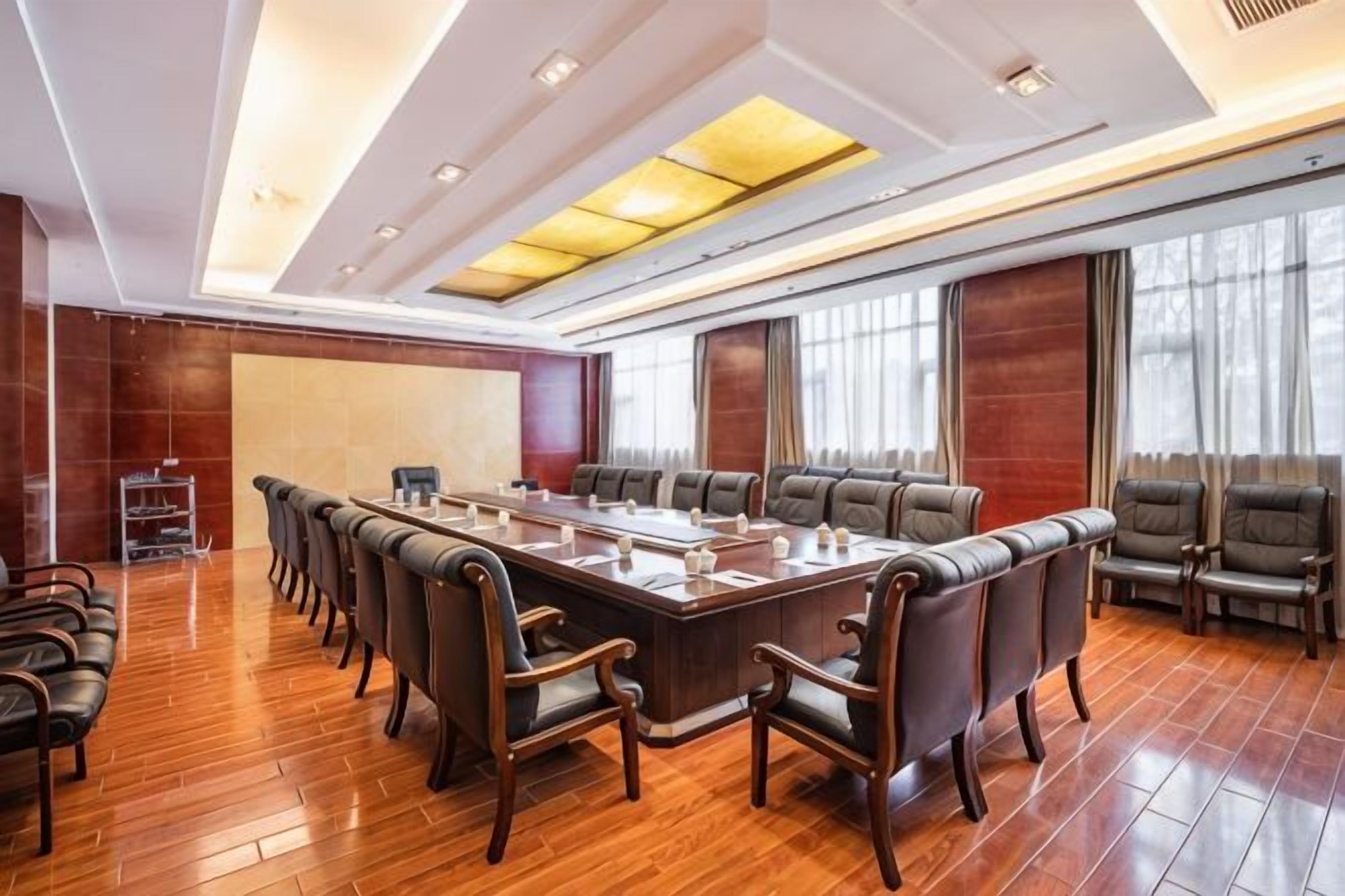 Un salón de conferencias con una mesa larga, varias sillas y suelo de madera.