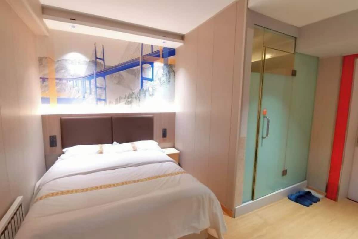 Ein Hotelzimmer mit Bett, Duschkabine und Blick auf eine Brücke durch ein Fenster.