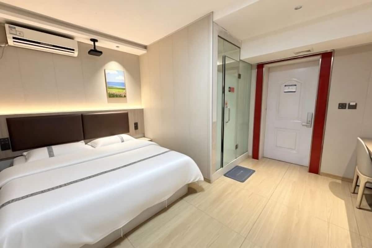 Ein Hotelzimmer mit Bett, Klimaanlage, Glastür und Tür.