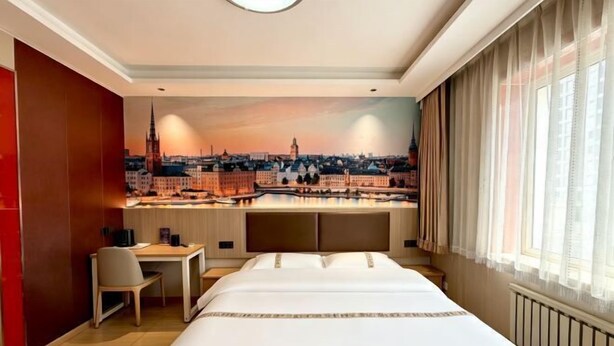 Habitación de hotel con cama, escritorio y vistas a la ciudad.
