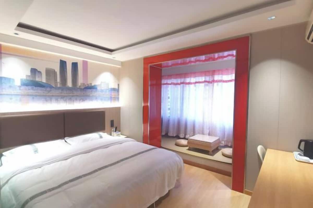 Ein Hotelzimmer mit Bett, Schreibtisch und einem Vorhangfenster.