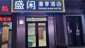 Entrada de un hotel con un letrero de neón que dice "SHENG XIAN HOTEL".