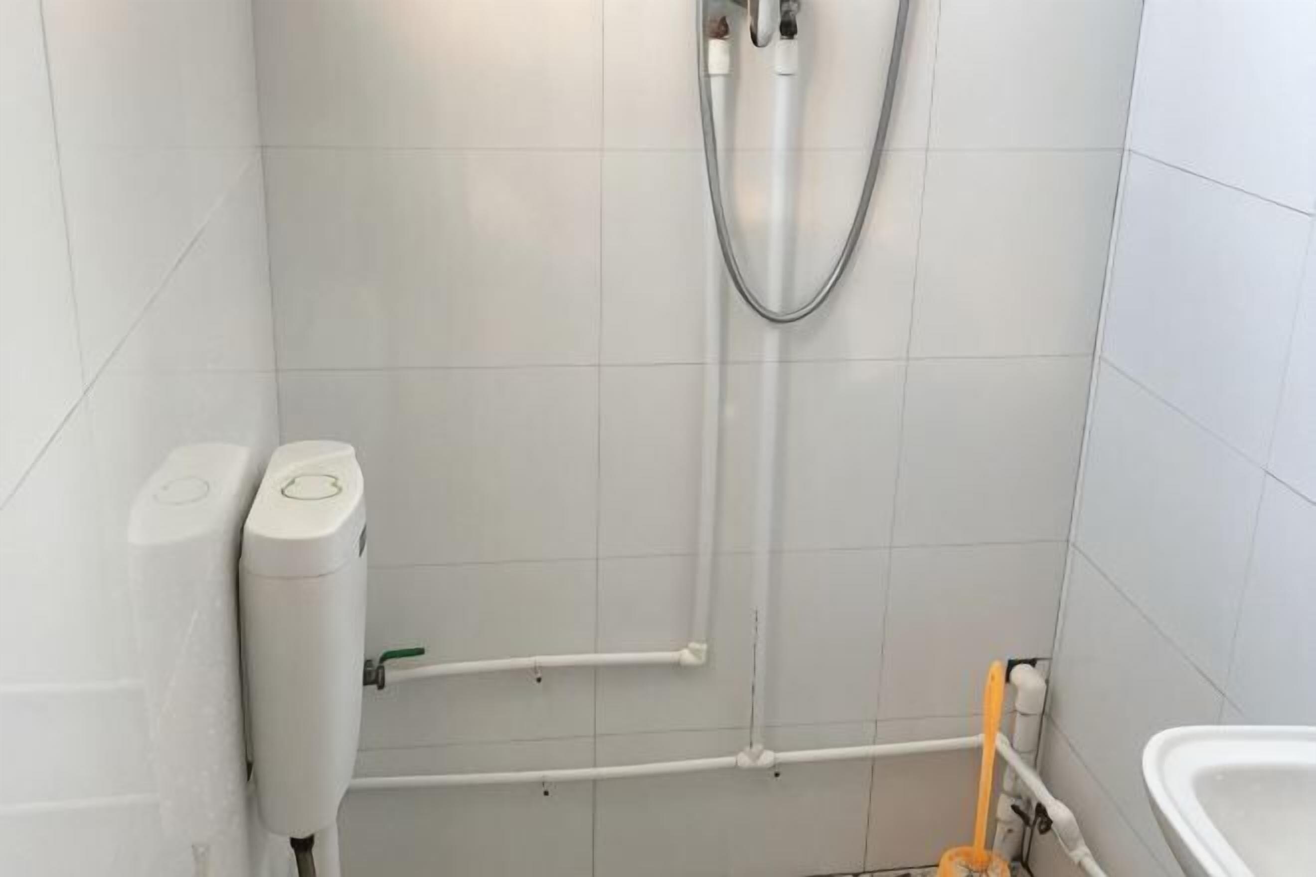 A bathroom with white tiles, a shower, a toilet, and a bidet.