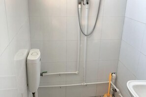 A bathroom with white tiles, a shower, a toilet, and a bidet. - Yuming Farmhouse (Tianjin)