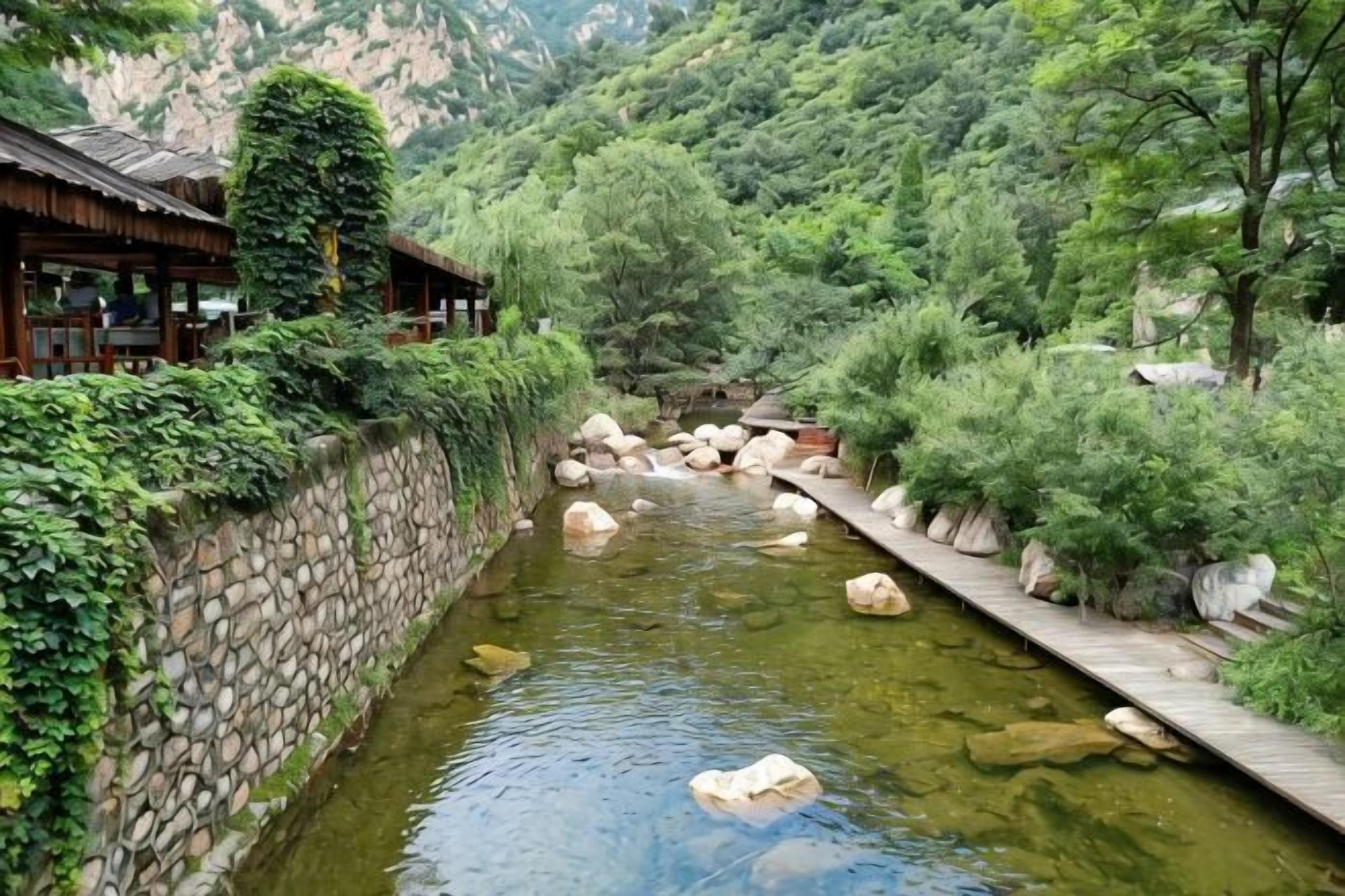 A traditional Japanese-style building with a stone wall and wooden deck along a river.