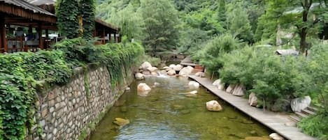 A traditional Japanese-style building with a stone wall and wooden deck along a river.
