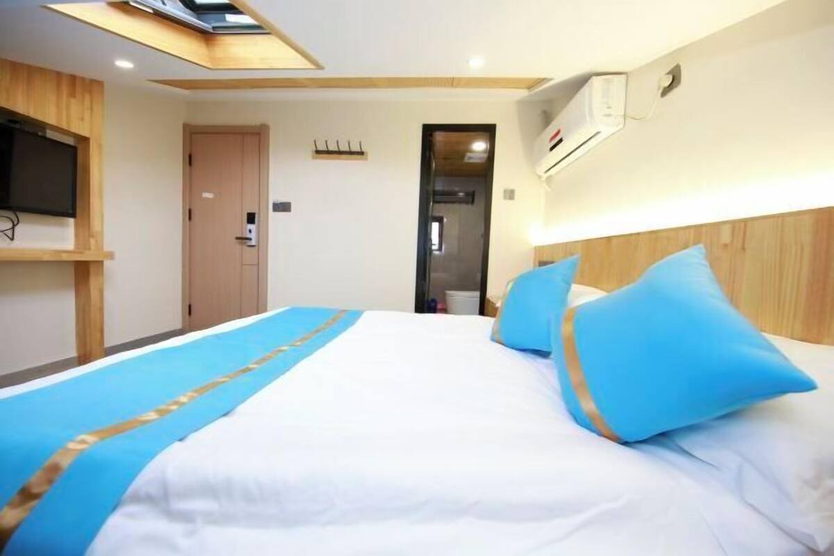 Een hotelkamer met een bed, een aan de muur bevestigde televisie, een deur en een klein raam.