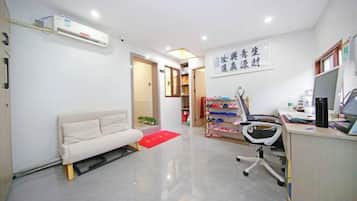Una habitación con sofá, escritorio con computadora y zapatero.