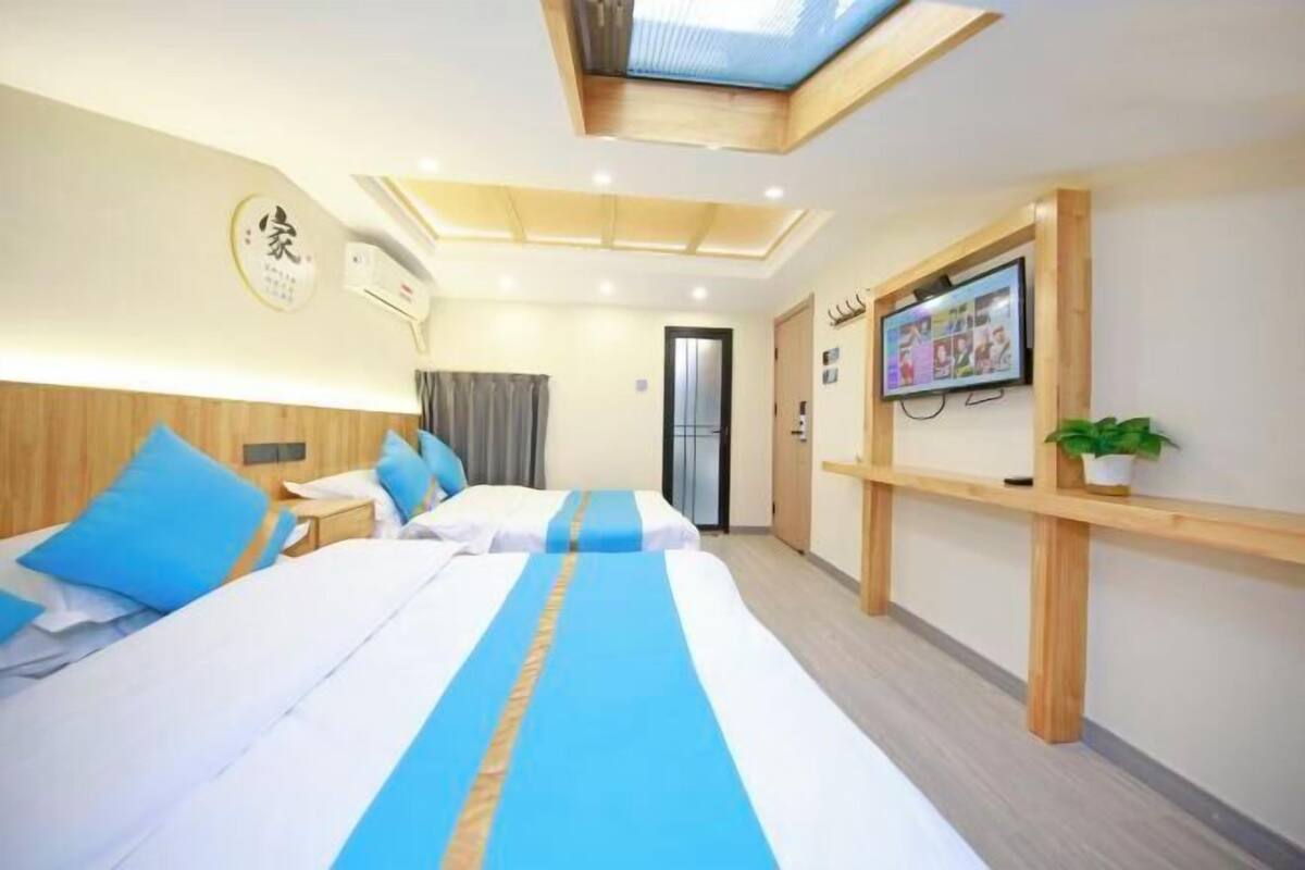 Een hotelkamer met twee bedden, een televisie aan de muur en een klein plantje op een plank.