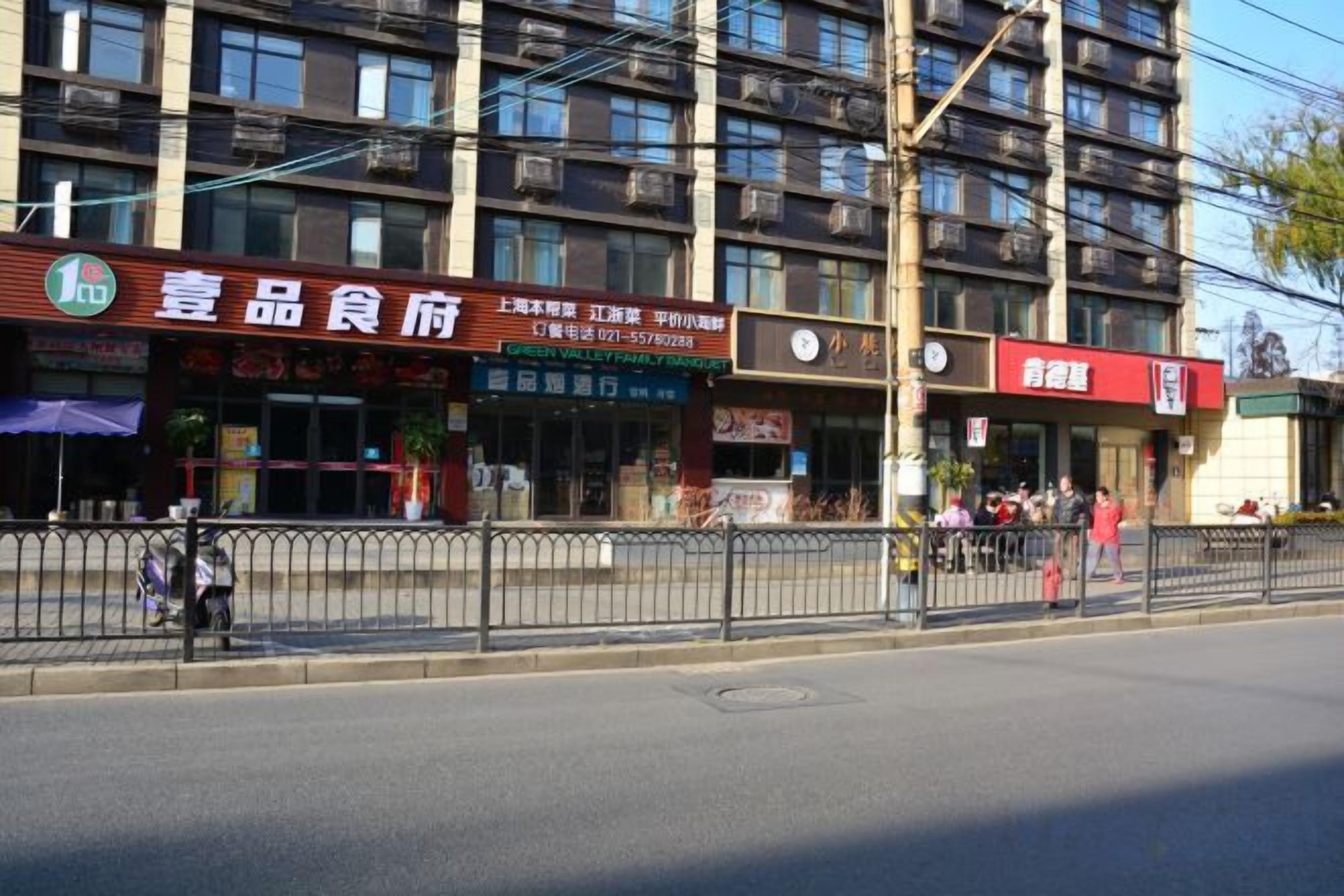A multi-story building with various commercial establishments on the ground floor, including a restaurant and a shop.