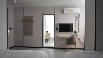 Een hotelkamer met een bed, een bureau met stoel, een televisie en een kledingkast.